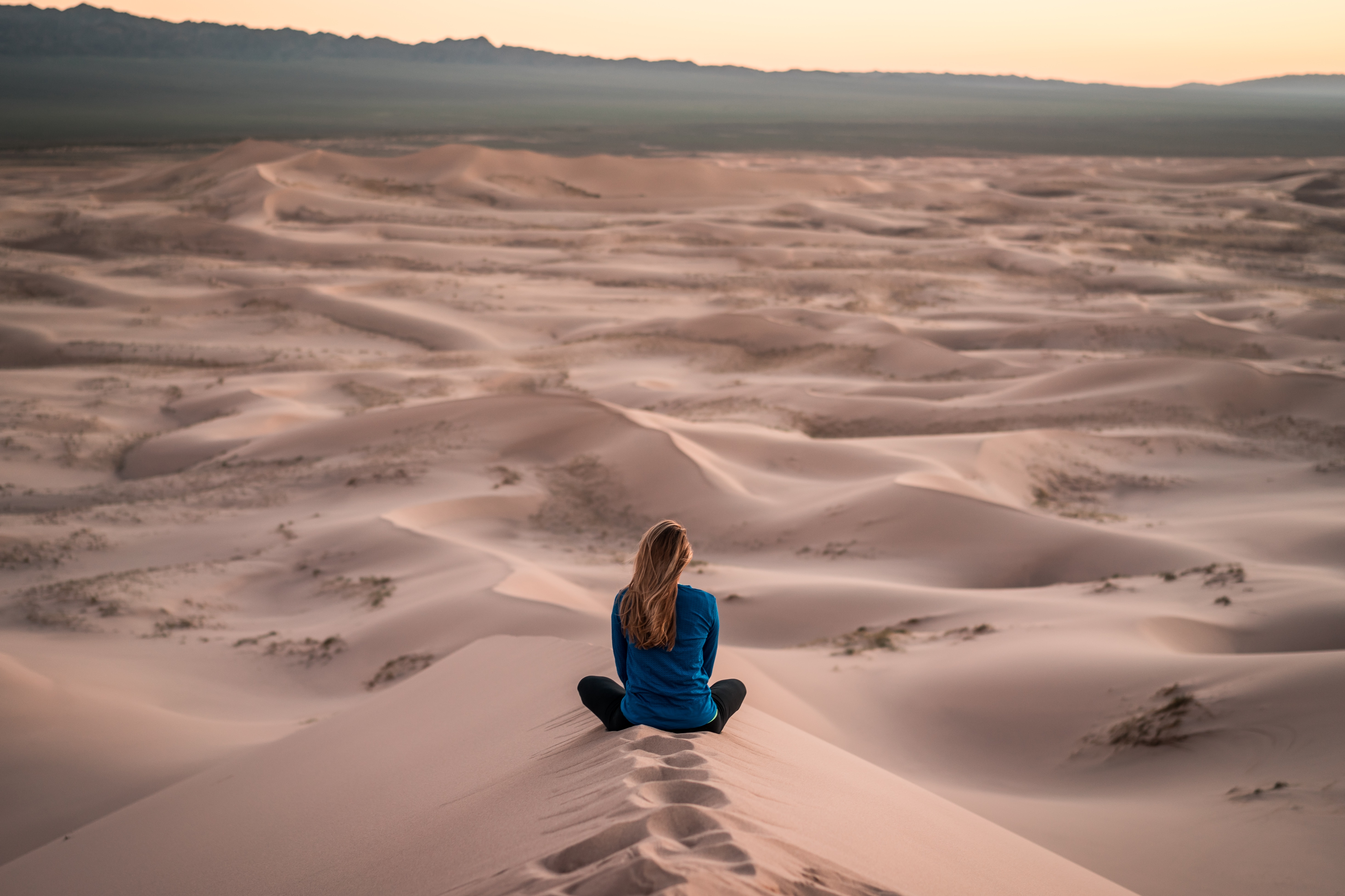 woman sitting in sand dune