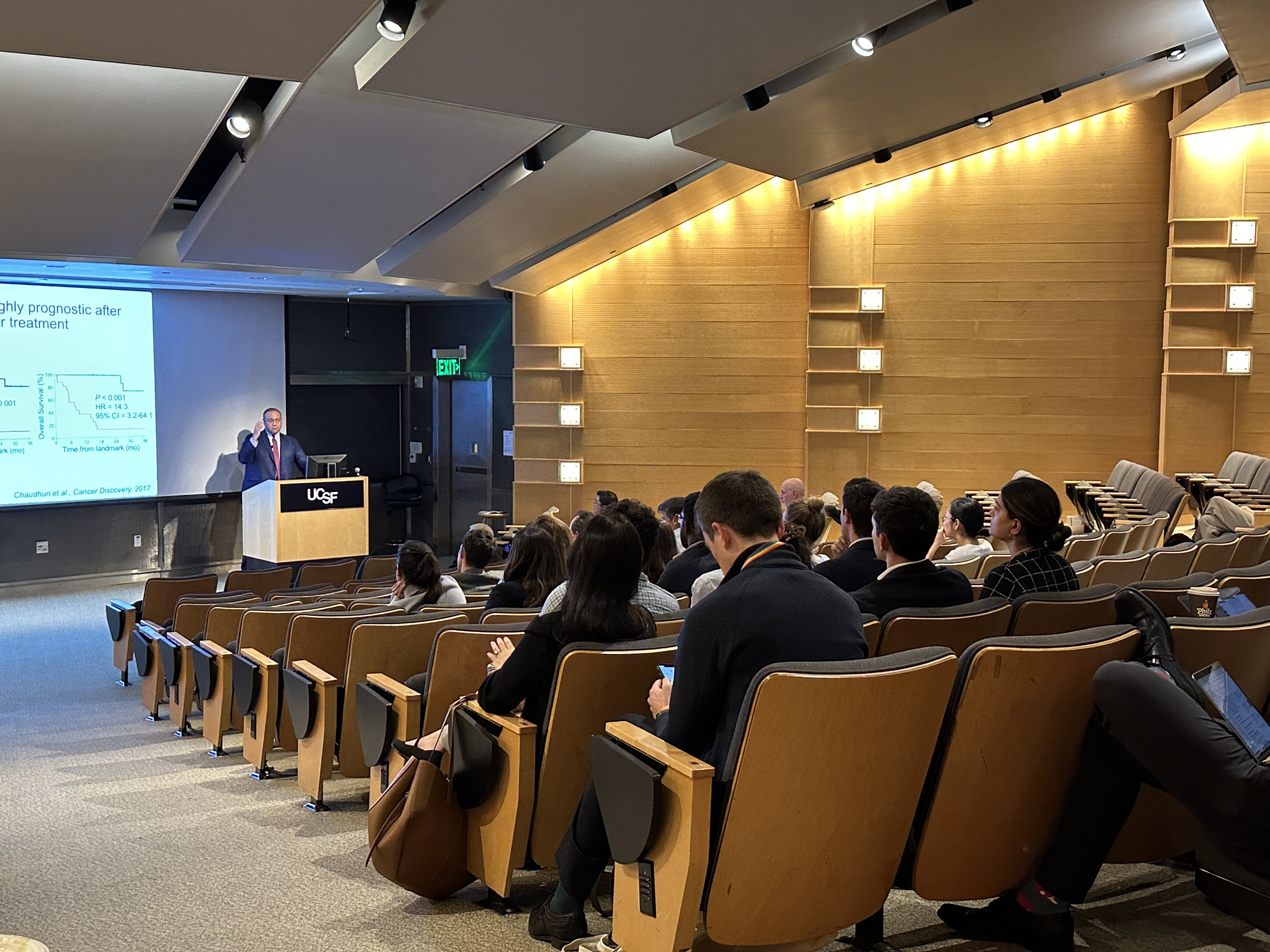 Dr. Zevallos stands at the front of an auditorium with a room full of attendees.