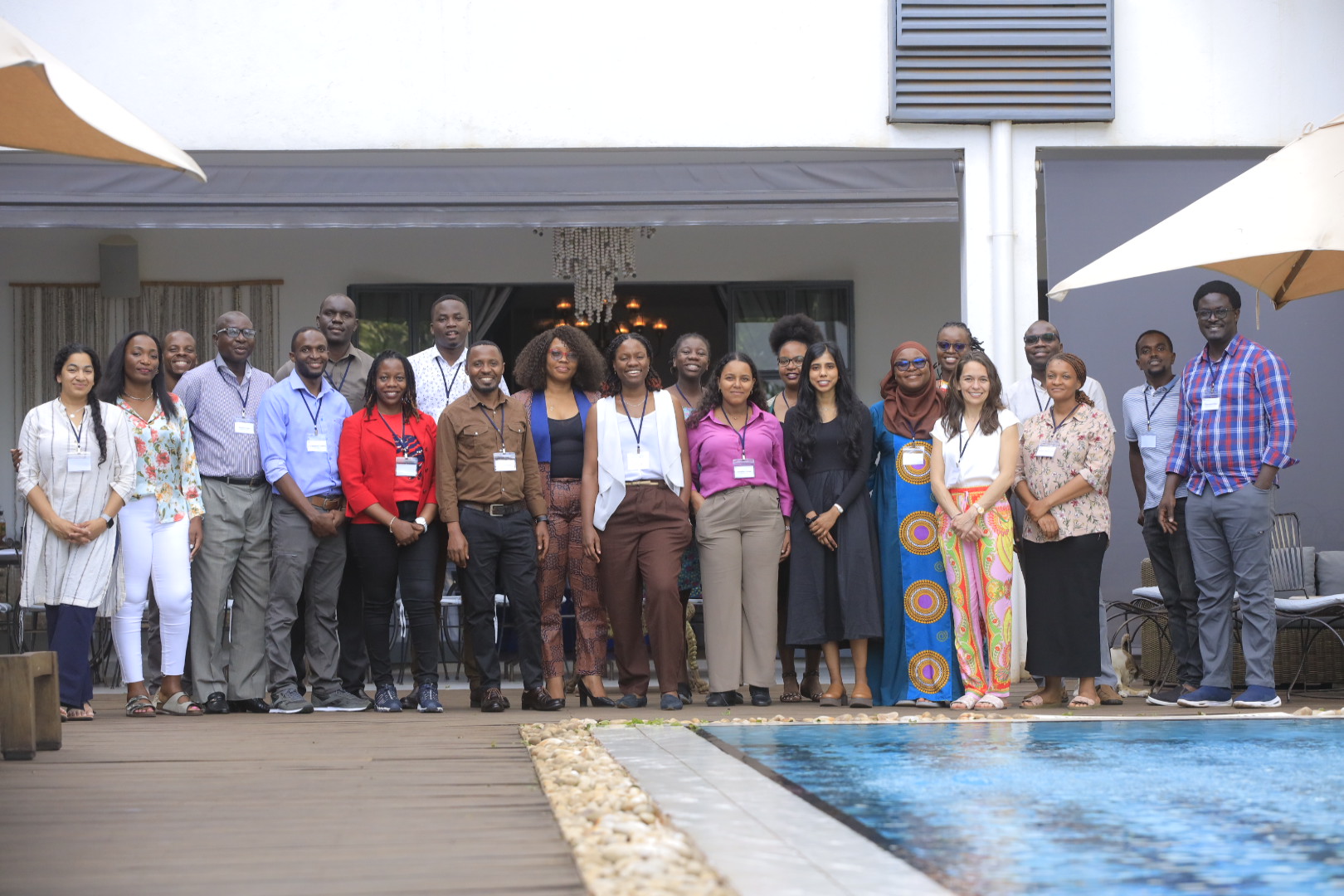 Dr. Lia Jacobson stands fourth from the right in a large group of people posing for a photo outdoors by a pool.