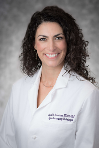 Headshot of Sarah Schneider, a white woman with dark curly hair wearing a white medical coat