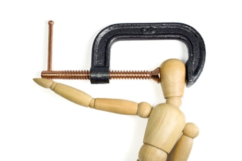 a-clamp-squeezing-tightly-on-the-head-of-a-wooden-man-a-great-concept-shot-for-headaches-or-stress