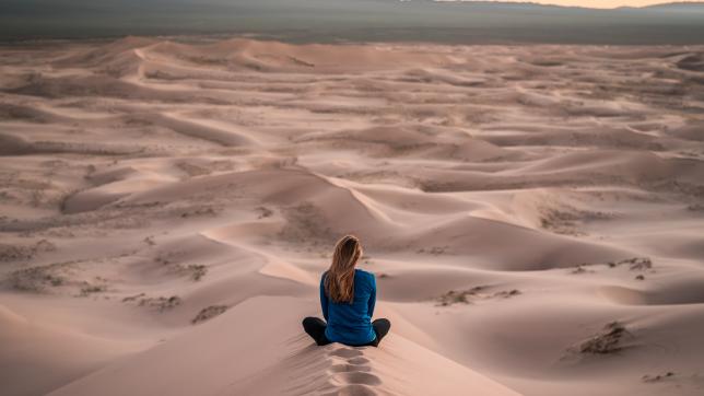 woman sitting in sand dune